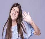 Photo smiling girl with thick eyebrows waving her hand